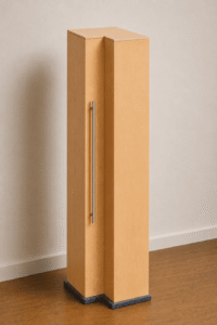 Ein hoher, schmaler Holzschrank mit einem langen Metallgriff, der auf einem dunklen Sockel vor einer hellen Wand steht.