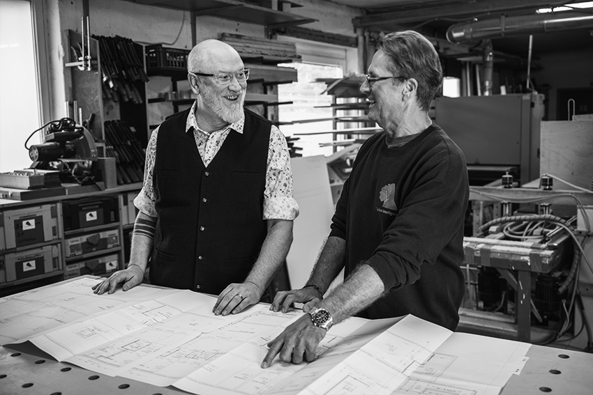 Zwei Mitarbeiter von Interlignum besprechen gemeinsam eine Möbelplanung in der Werkstatt.