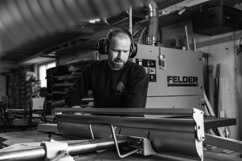 Tischler von Interlignum bei der Arbeit an einer Holzbearbeitungsmaschine in der Werkstatt.